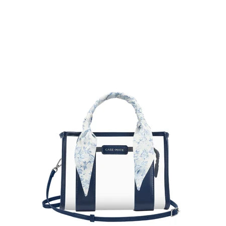 A Case-Mate structured handbag with a white and navy blue vertical stripe design, featuring a light blue and white floral silk scarf tied around the top handle, and a navy blue shoulder strap.