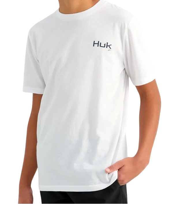 A smiling boy with short dark hair and braces wearing a white short-sleeve crewneck t-shirt with a small black 'Huk' logo on the left chest, set against a plain white background.