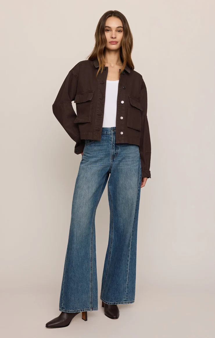 woman standing in jeans white top with canvas button up jacket 