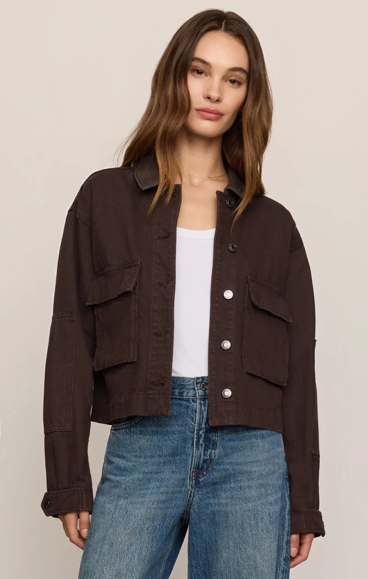 woman standing in jeans white top with canvas button up jacket 