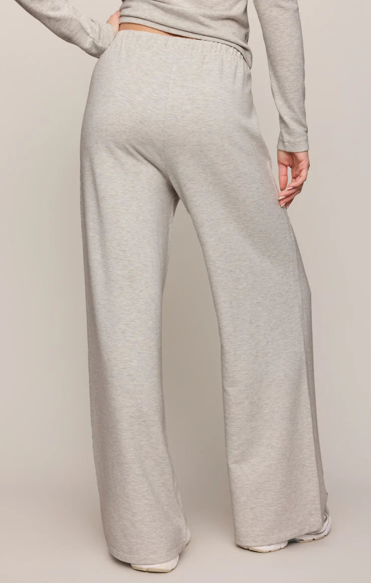 A person shown from the back wearing light heather gray wide-leg sweatpants and a matching long-sleeve top against a plain beige studio background.