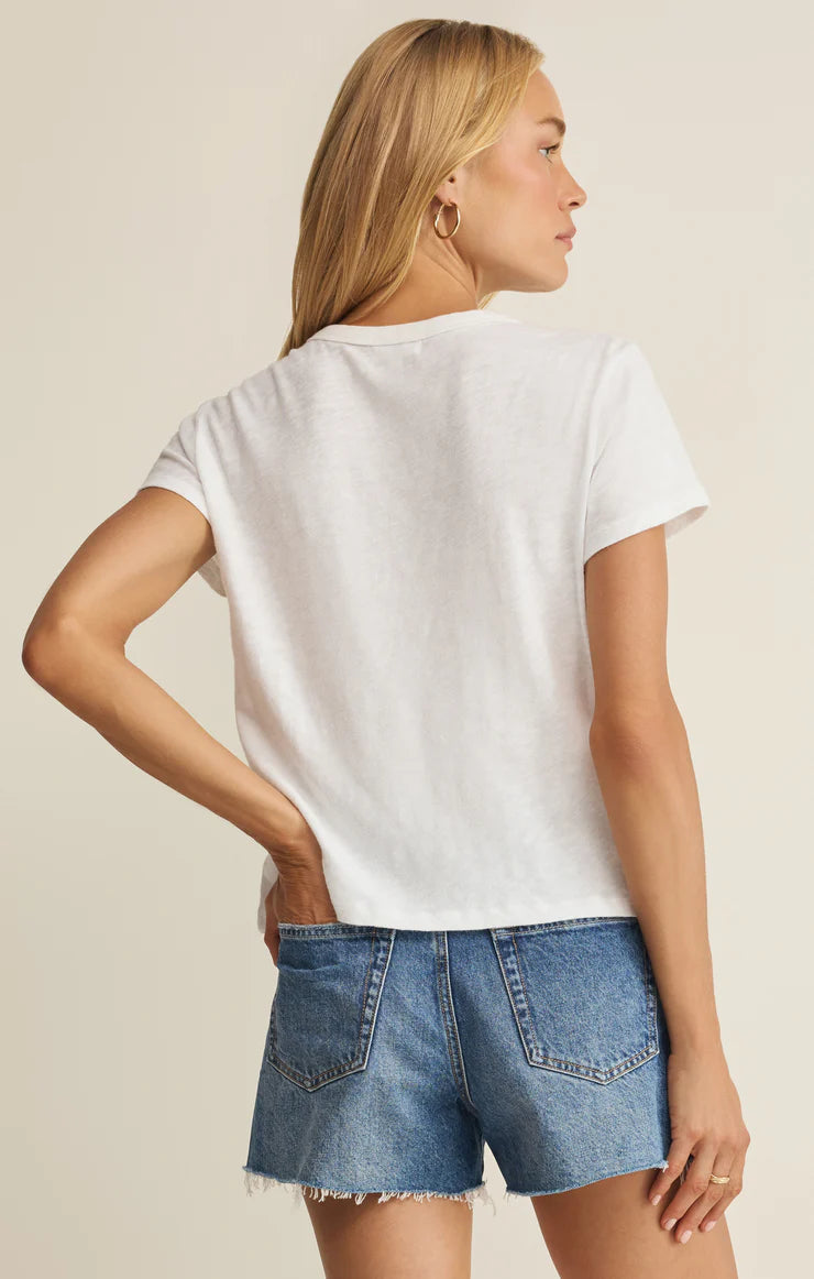 woman facing away modeling a white tee shirt with hand in pocket 