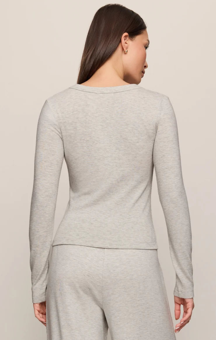 Woman wearing a gray long-sleeve top and pants on a beige background