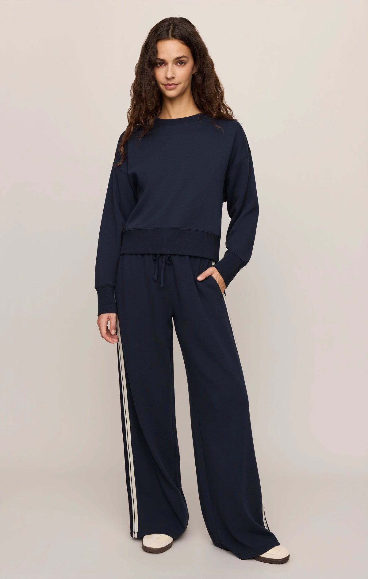 Woman wearing a navy blue outfit with wide-leg pants on a plain background