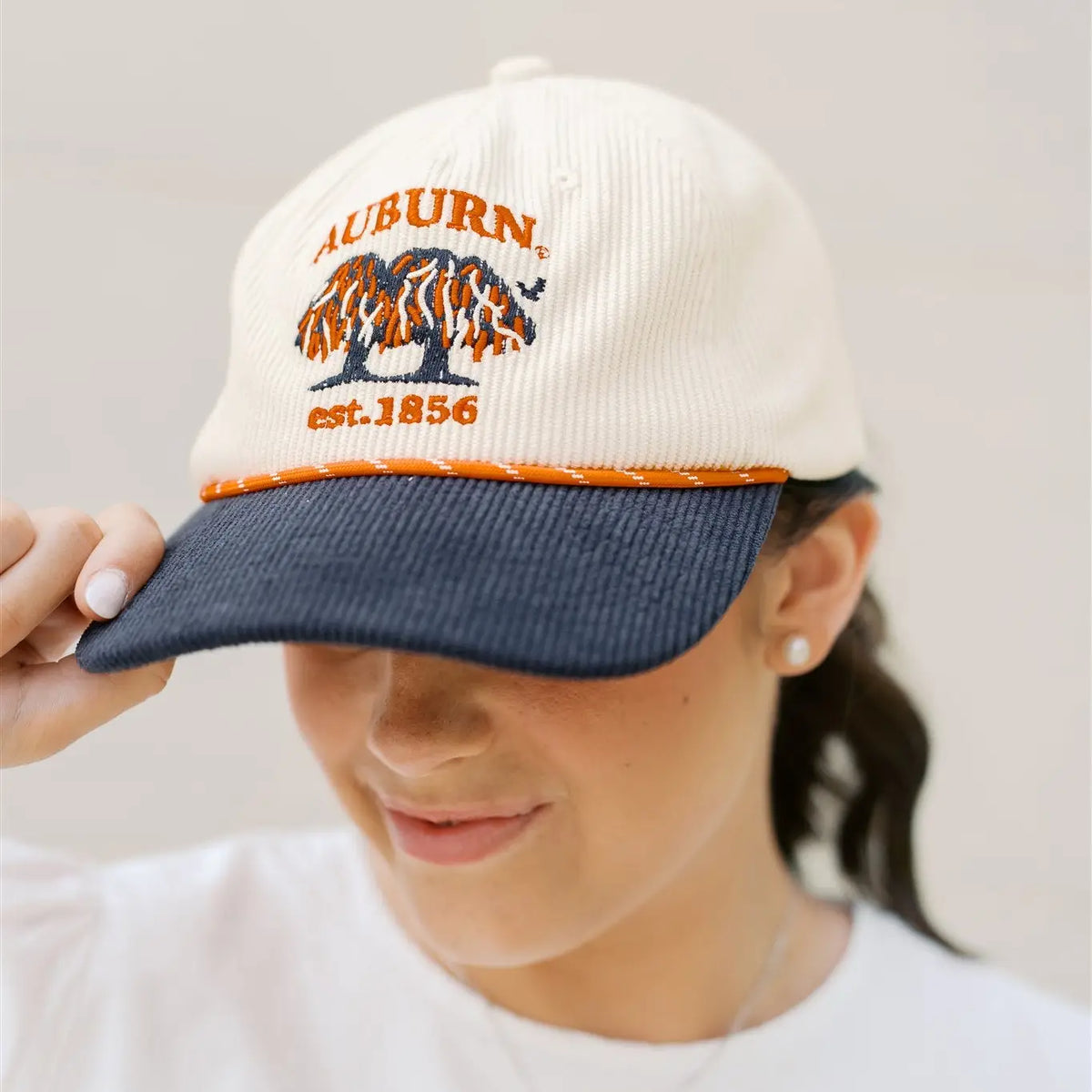 Person wearing a cap with 'Auburn est. 1856' design on a plain background