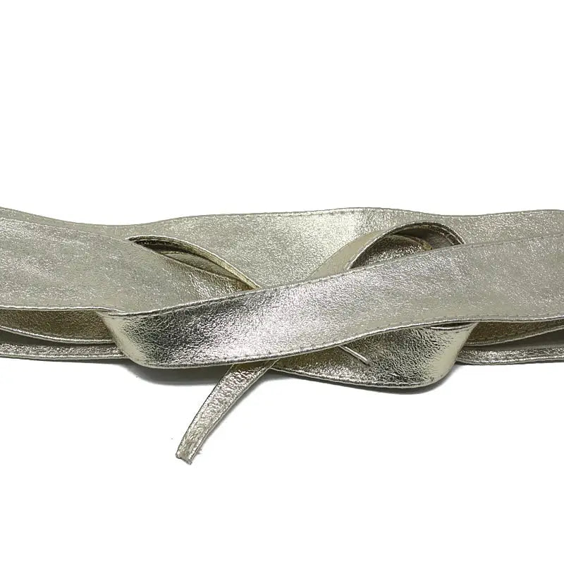 A close-up of a metallic silver faux leather ribbon or strap, folded and layered with a textured, crinkled finish, set against a plain white background.