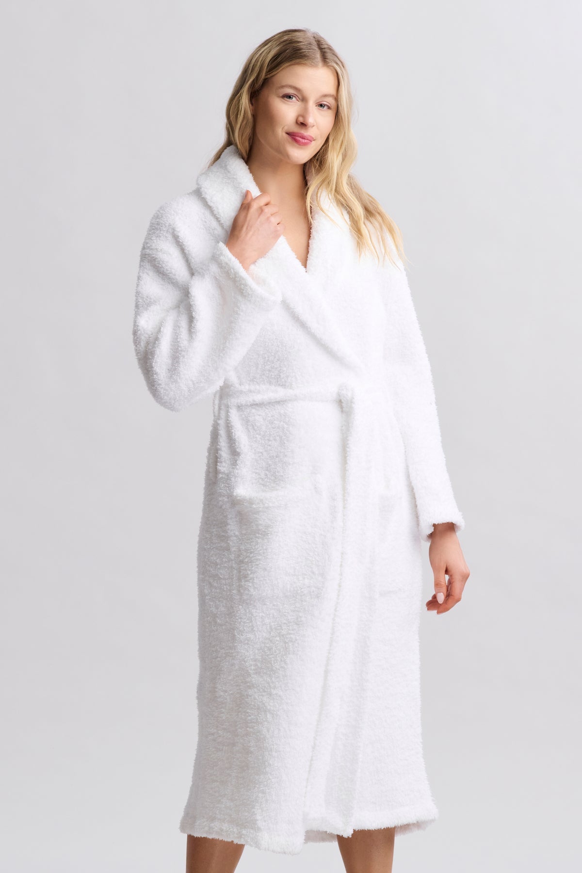 Woman wearing a white robe against a plain background