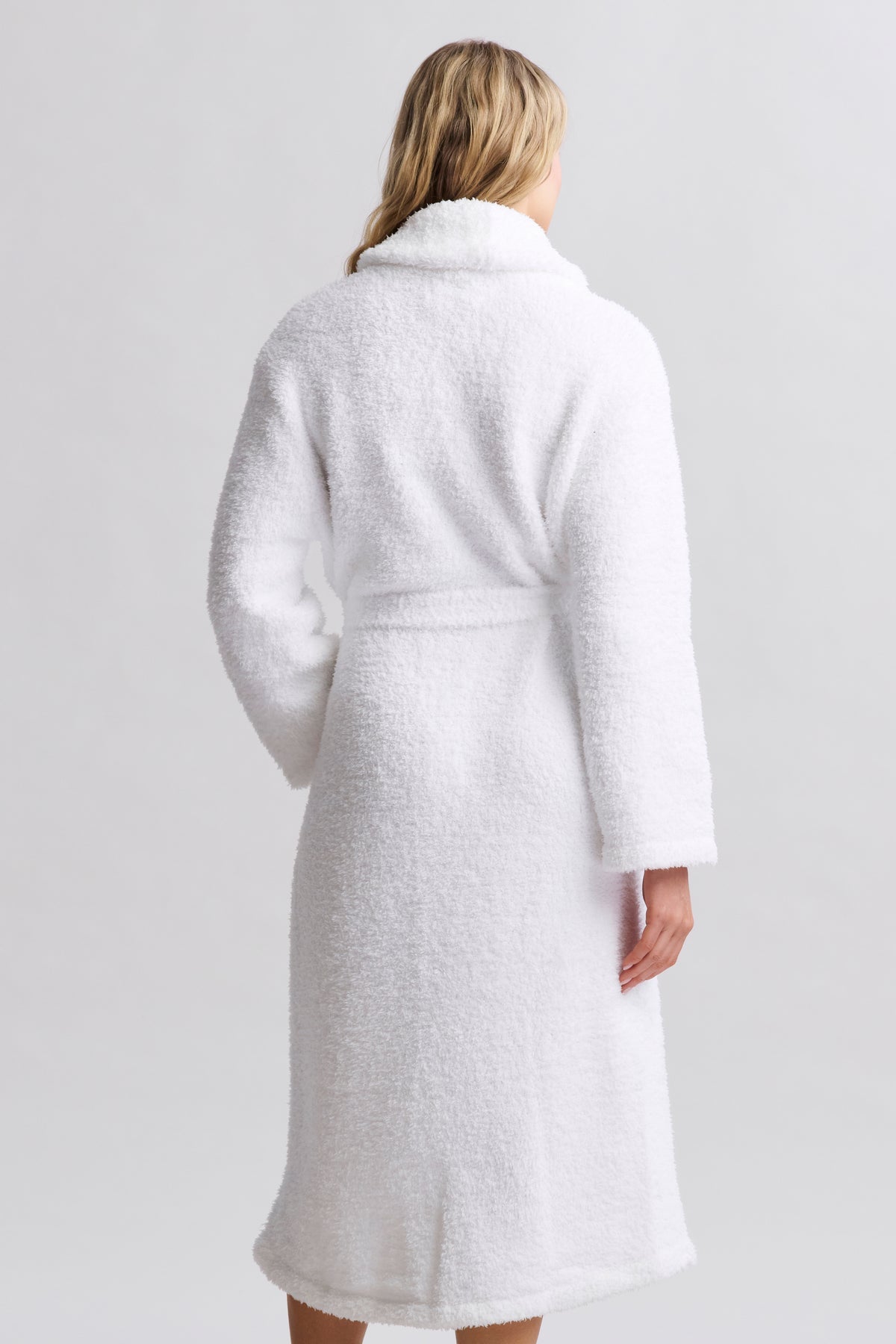 Person wearing a white textured coat on a plain background