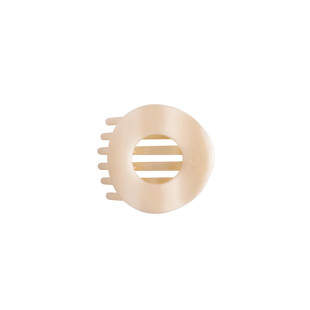 A cream-colored plastic hair claw clip with a circular design and four teeth on the side, shown against a plain white background.