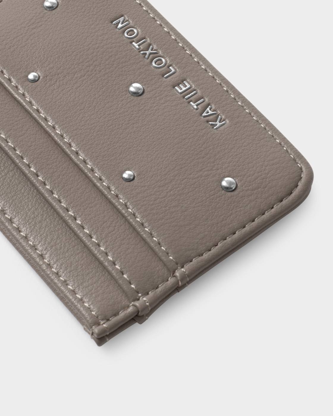 Close-up of a beige leather cardholder with studded details on a light gray background