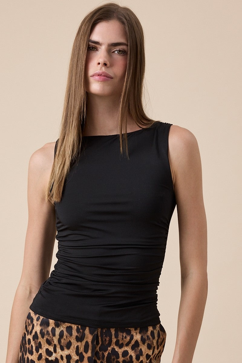 Woman wearing a black sleeveless top with a leopard print skirt on a beige background