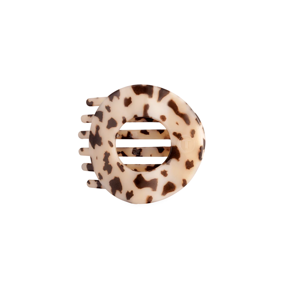 A circular hair claw clip with a tortoiseshell pattern in cream and dark brown, shown on a plain white background.