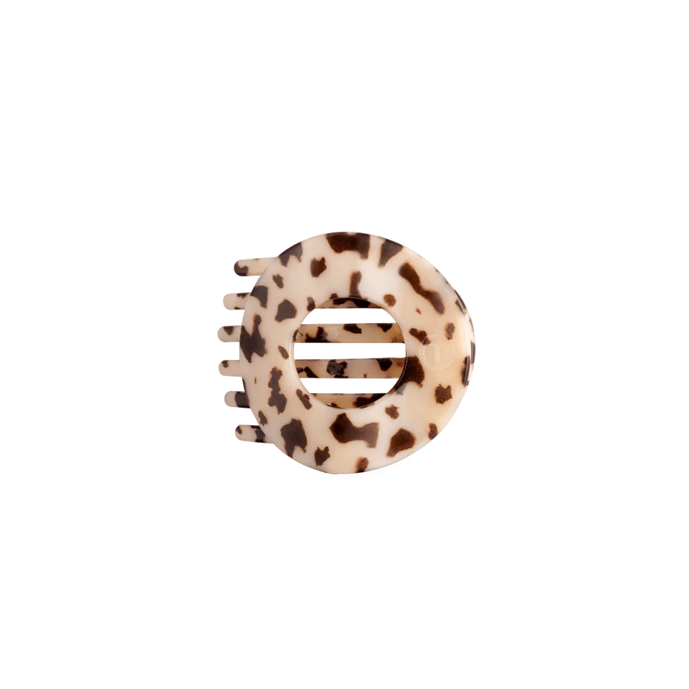 A tortoiseshell hair claw clip with a cream-colored base and dark brown spots, shown on a plain white background.