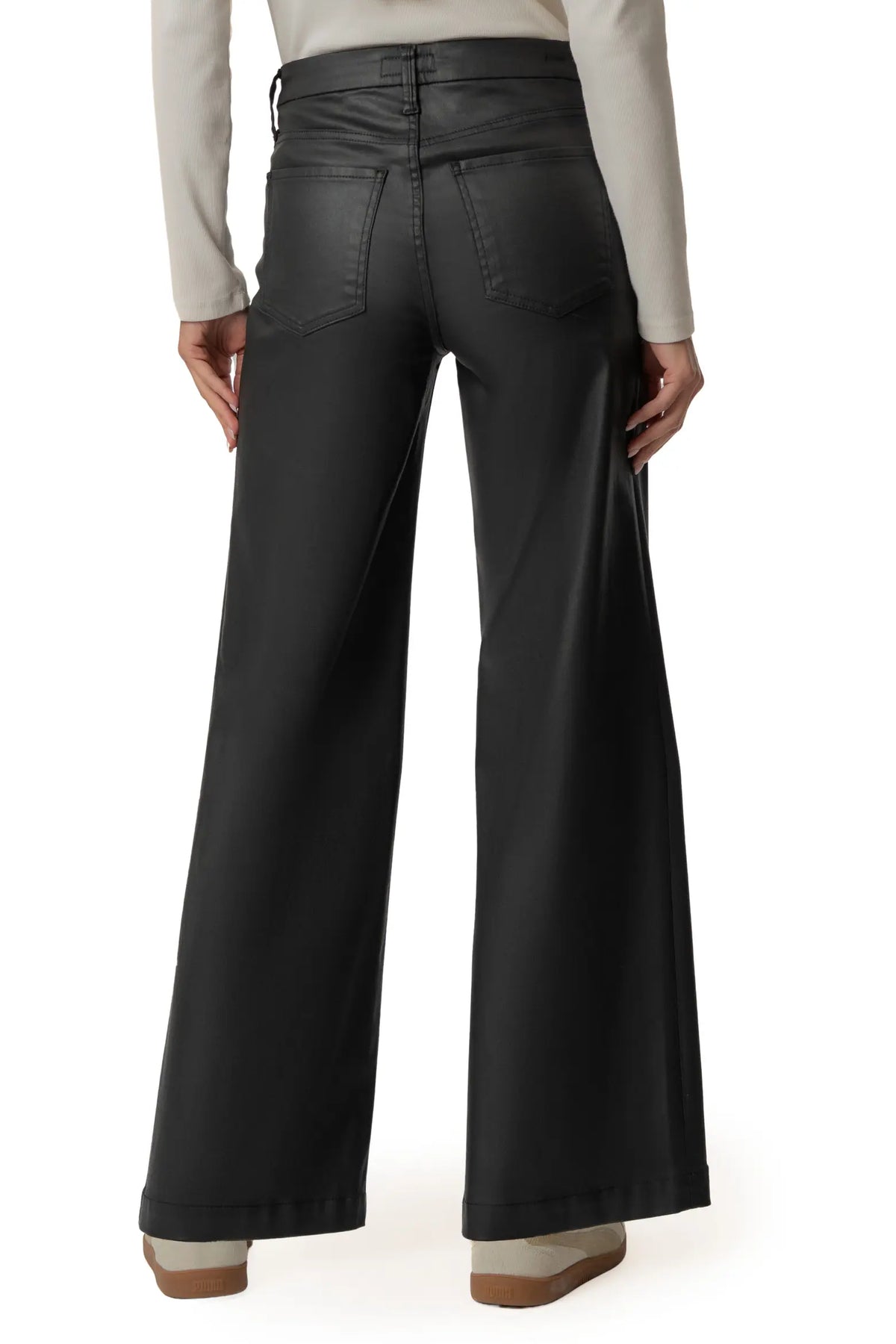 Black wide-leg pants shown from the back on a model, paired with a light beige long-sleeve top and brown shoes, against a plain white background.