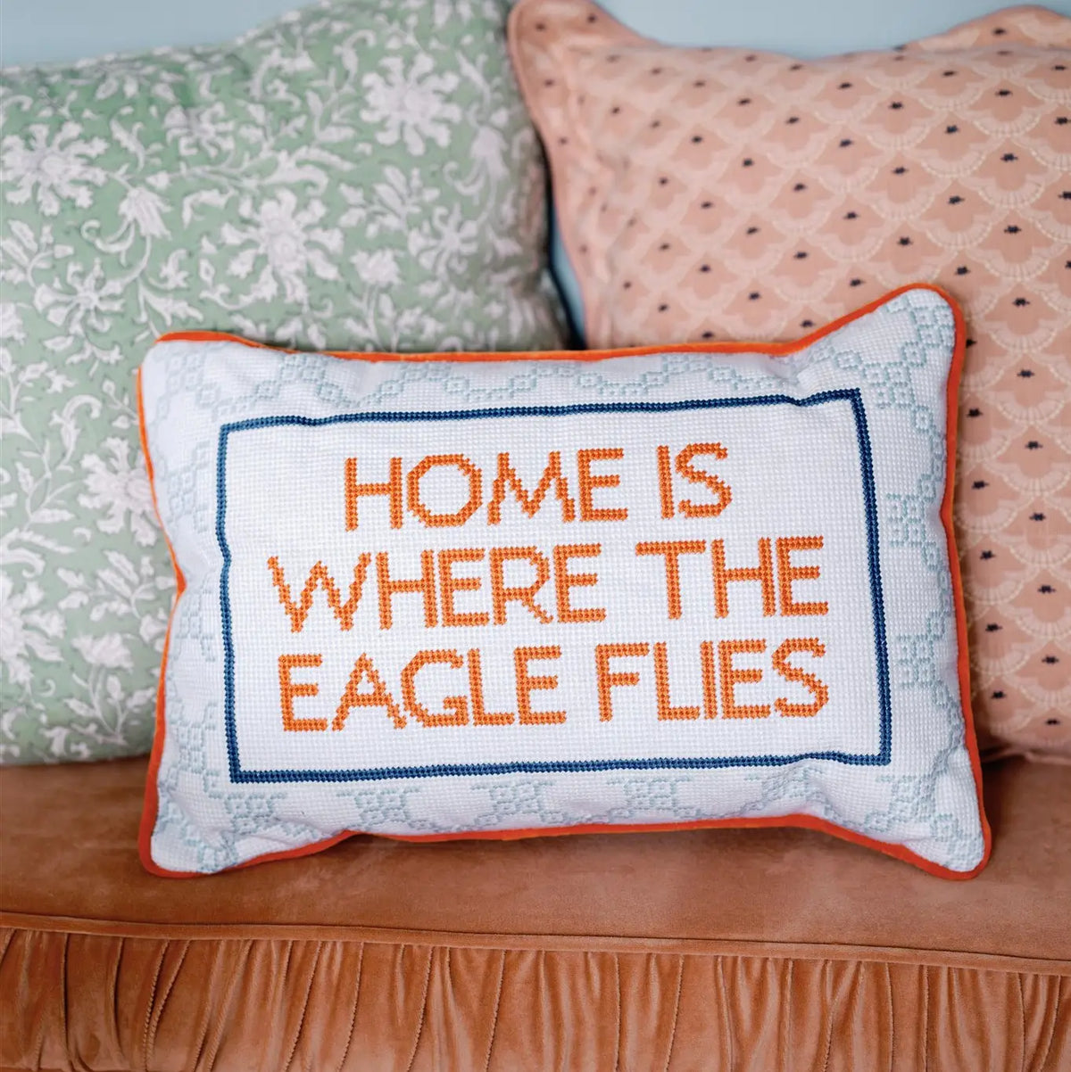 Decorative pillow with 'Home is where the eagle flies' text on a couch.