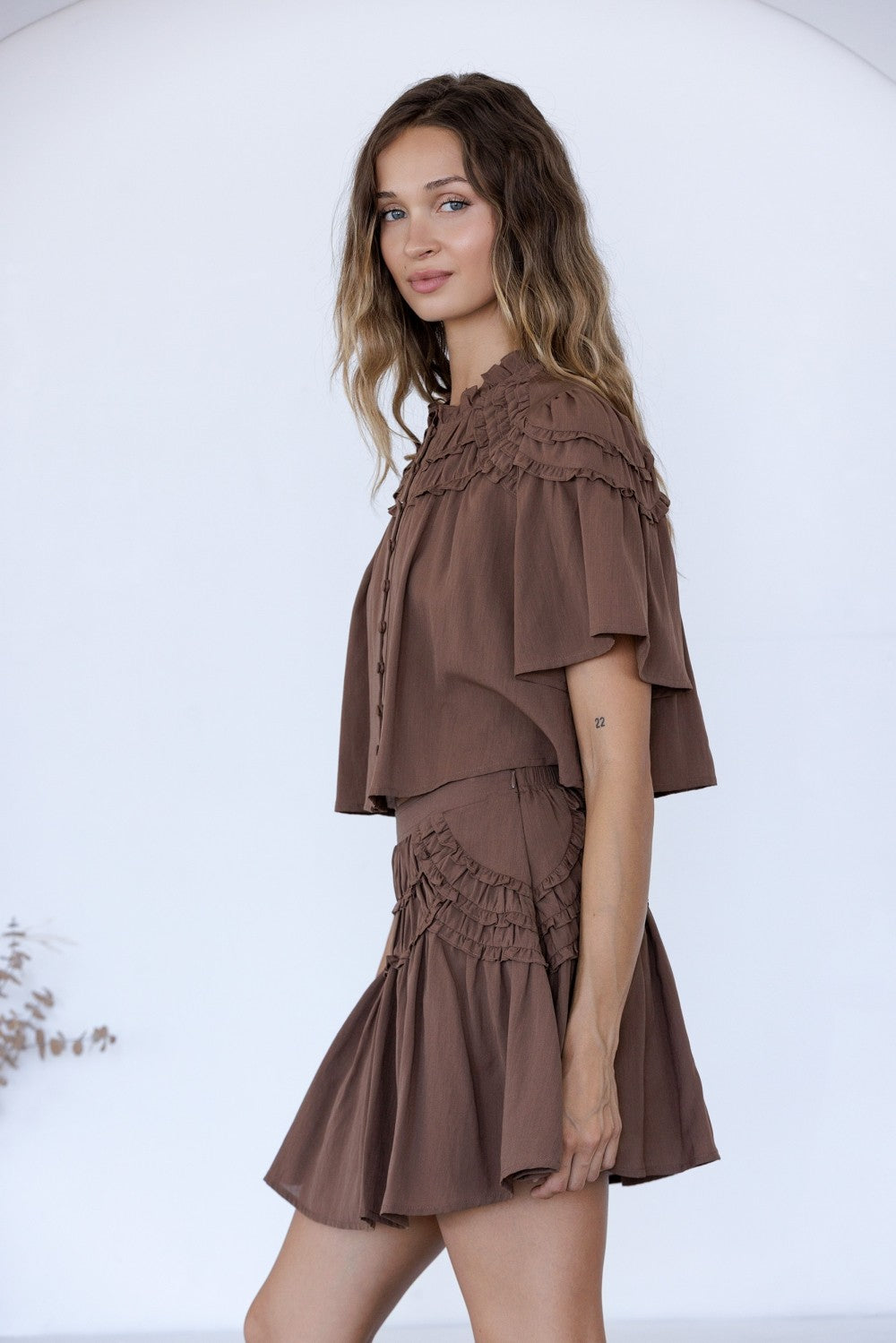 woman standing on white background wearing a matching brown set