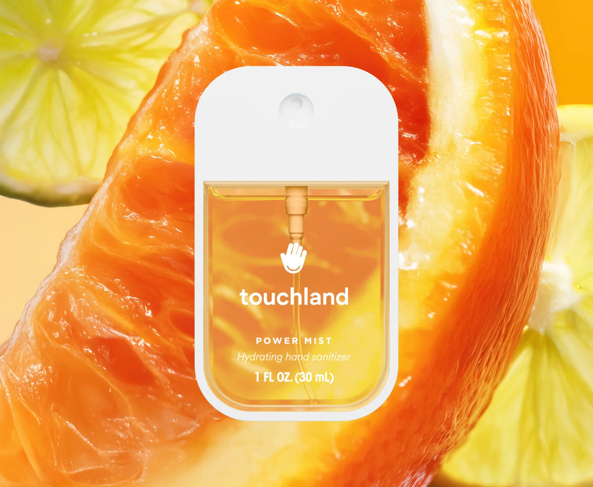 Touchland hand sanitizer bottle with orange and lemon slices in the background