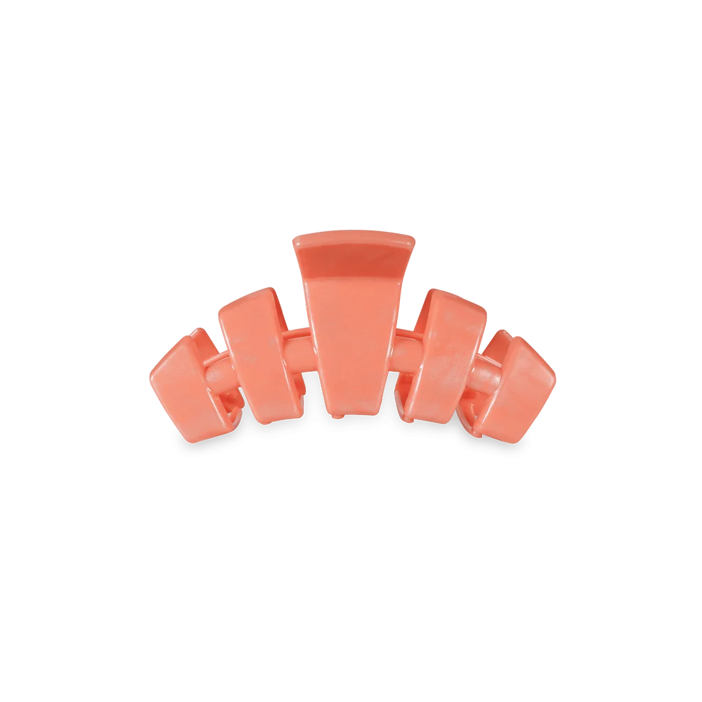 A coral pink hair claw clip shown against a solid white background.