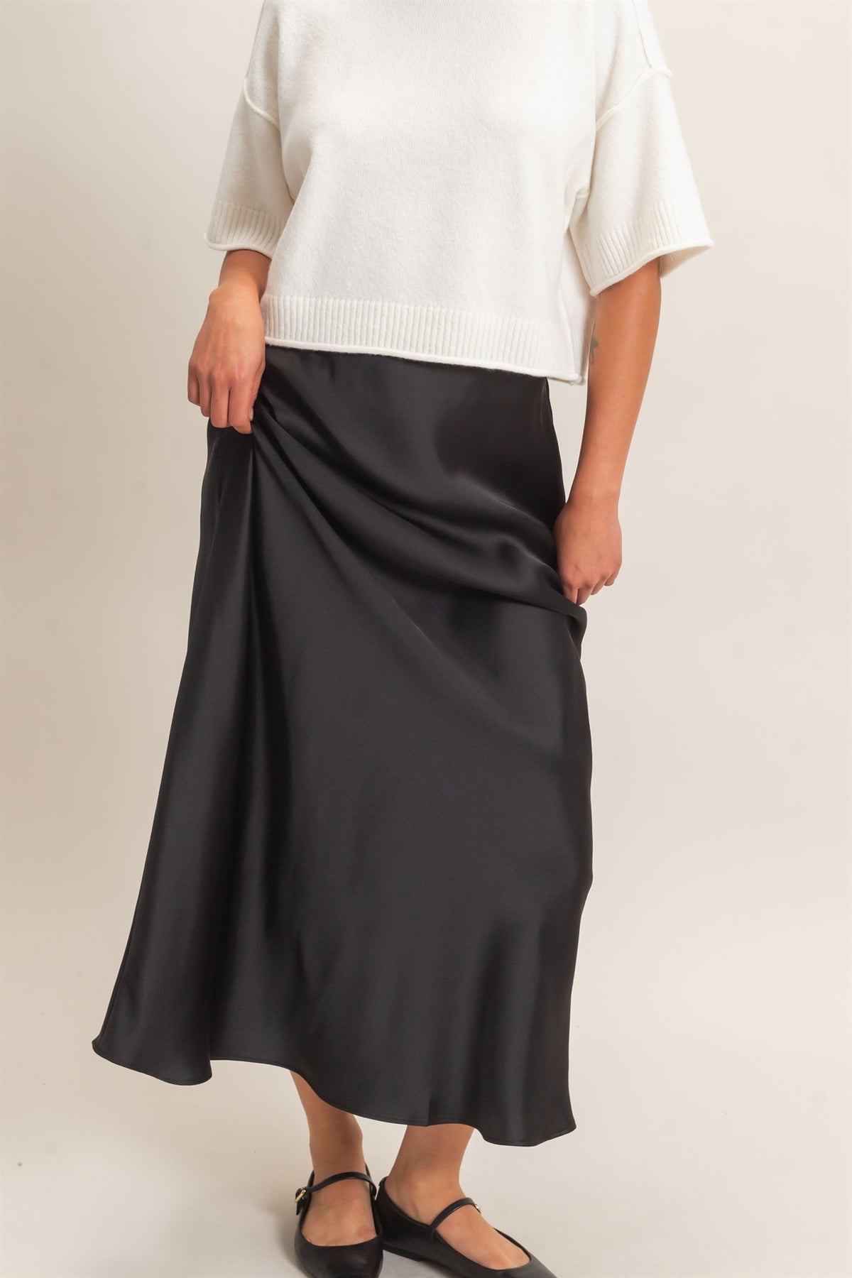 Person wearing a black skirt and white top on a plain background