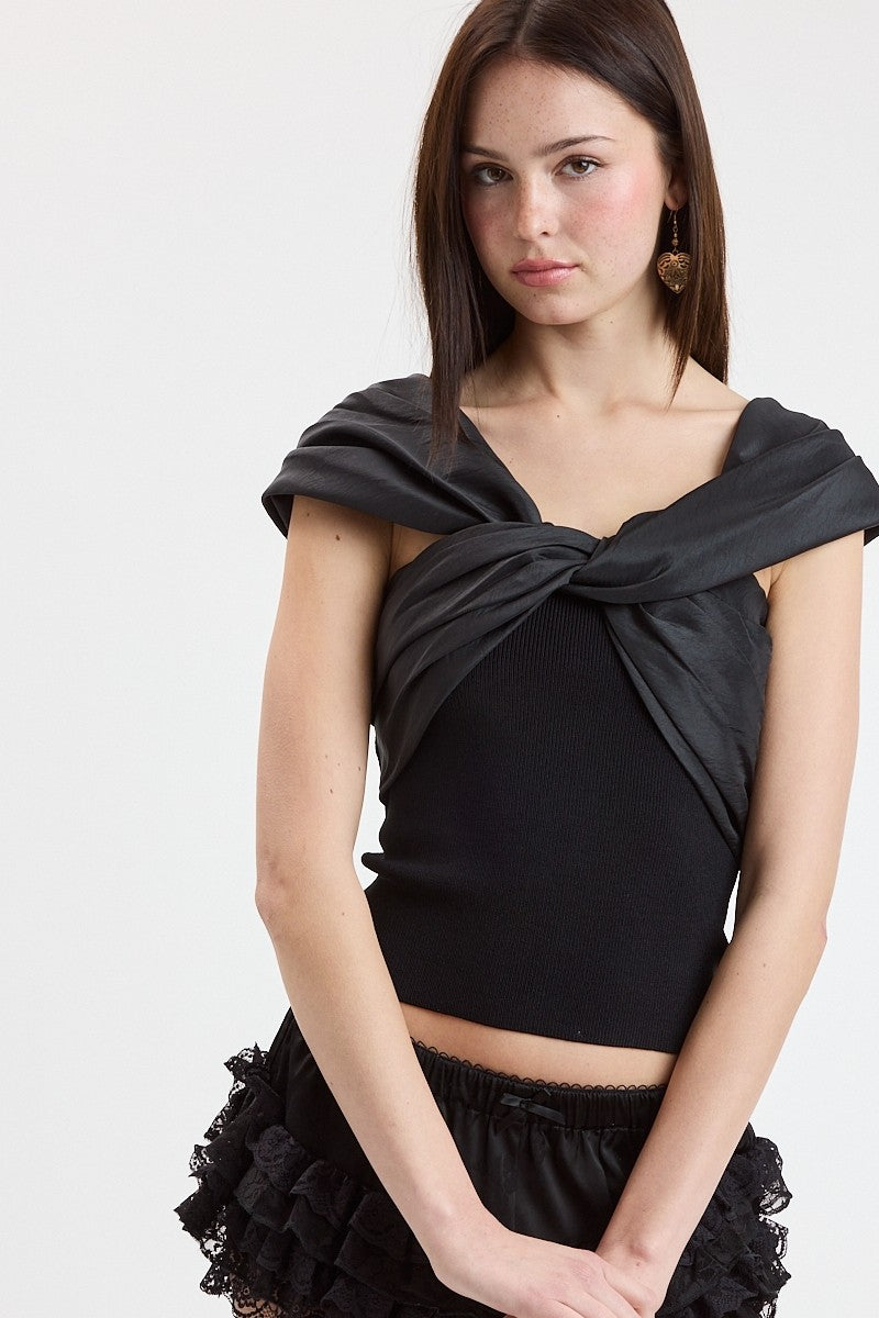 Woman wearing a black top with a draped design on a white background