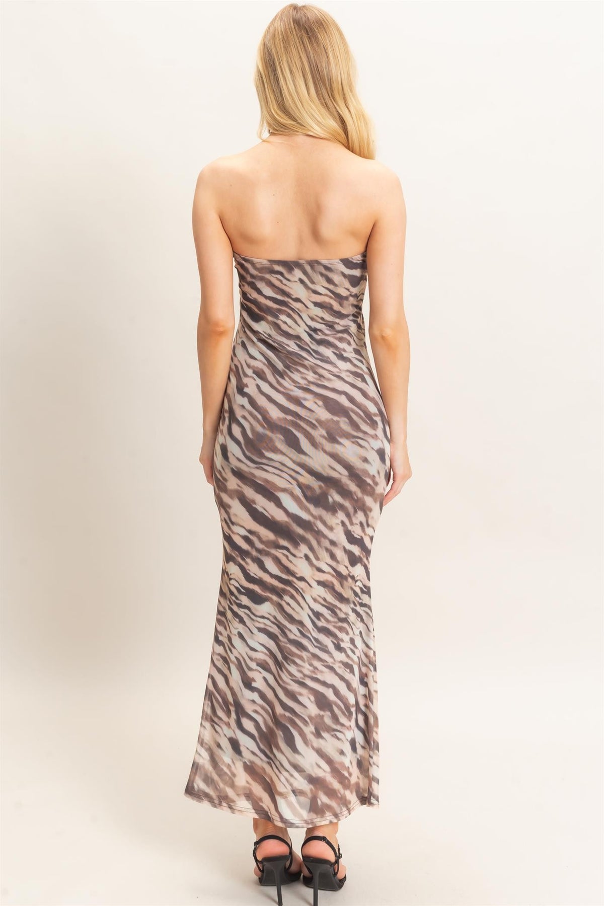 Woman wearing a strapless dress with a zebra print pattern on a plain background