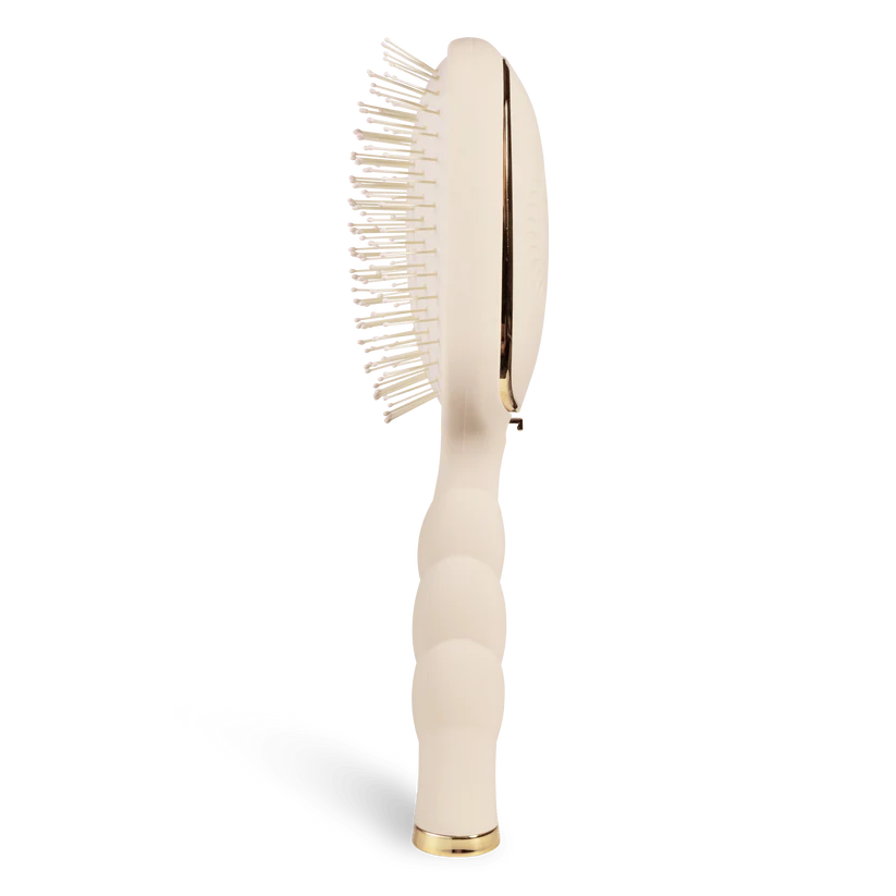 Beige hairbrush with gold accents on a white background