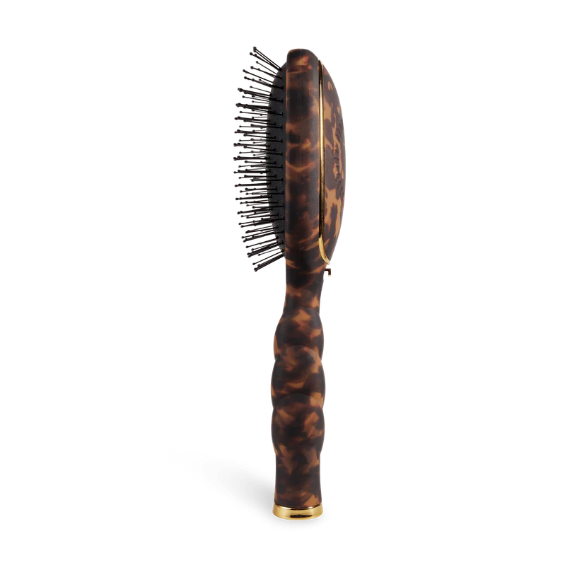Tortoiseshell hairbrush with gold accents on a white background