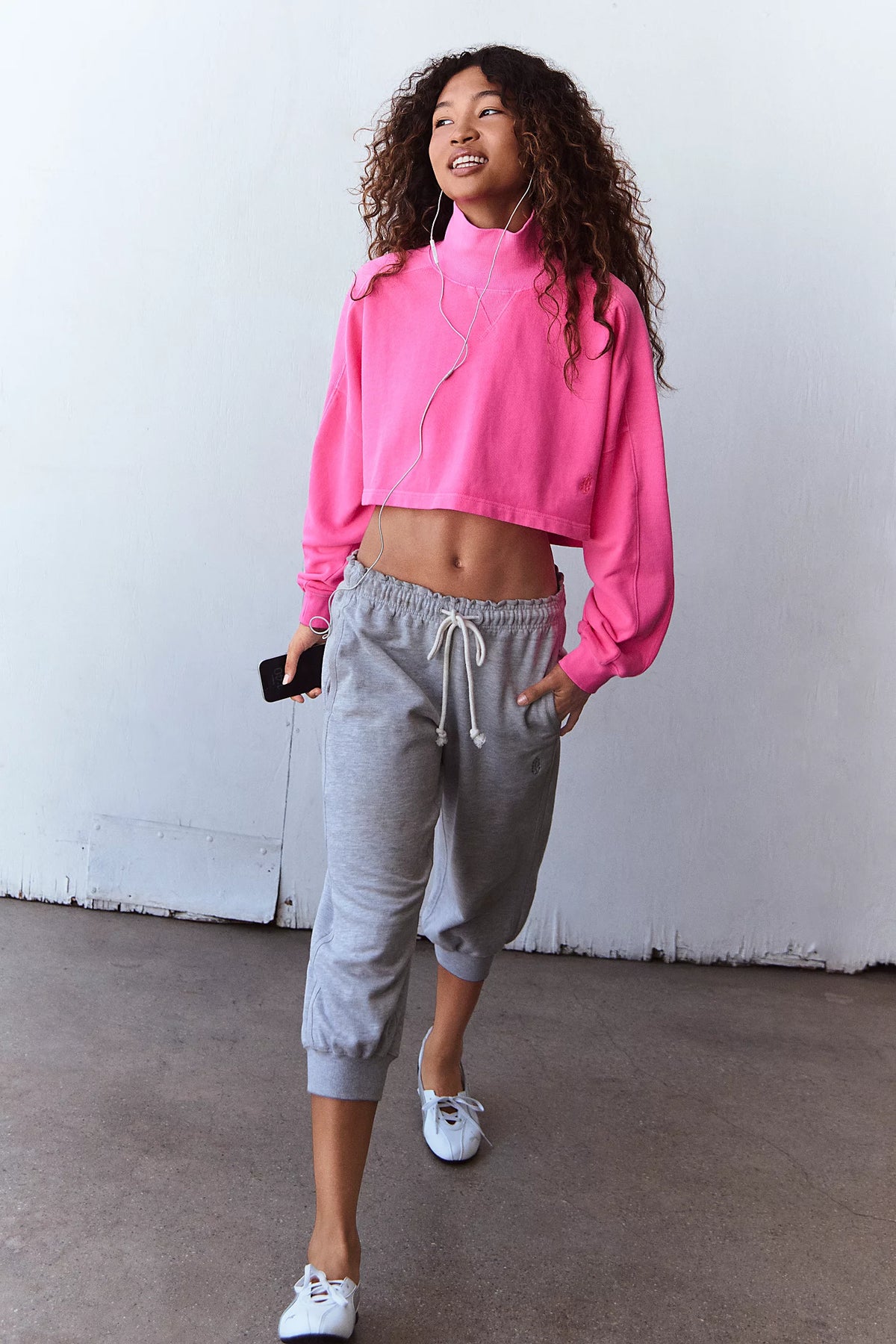 Women standing with pink sweatshirt and grey pants.