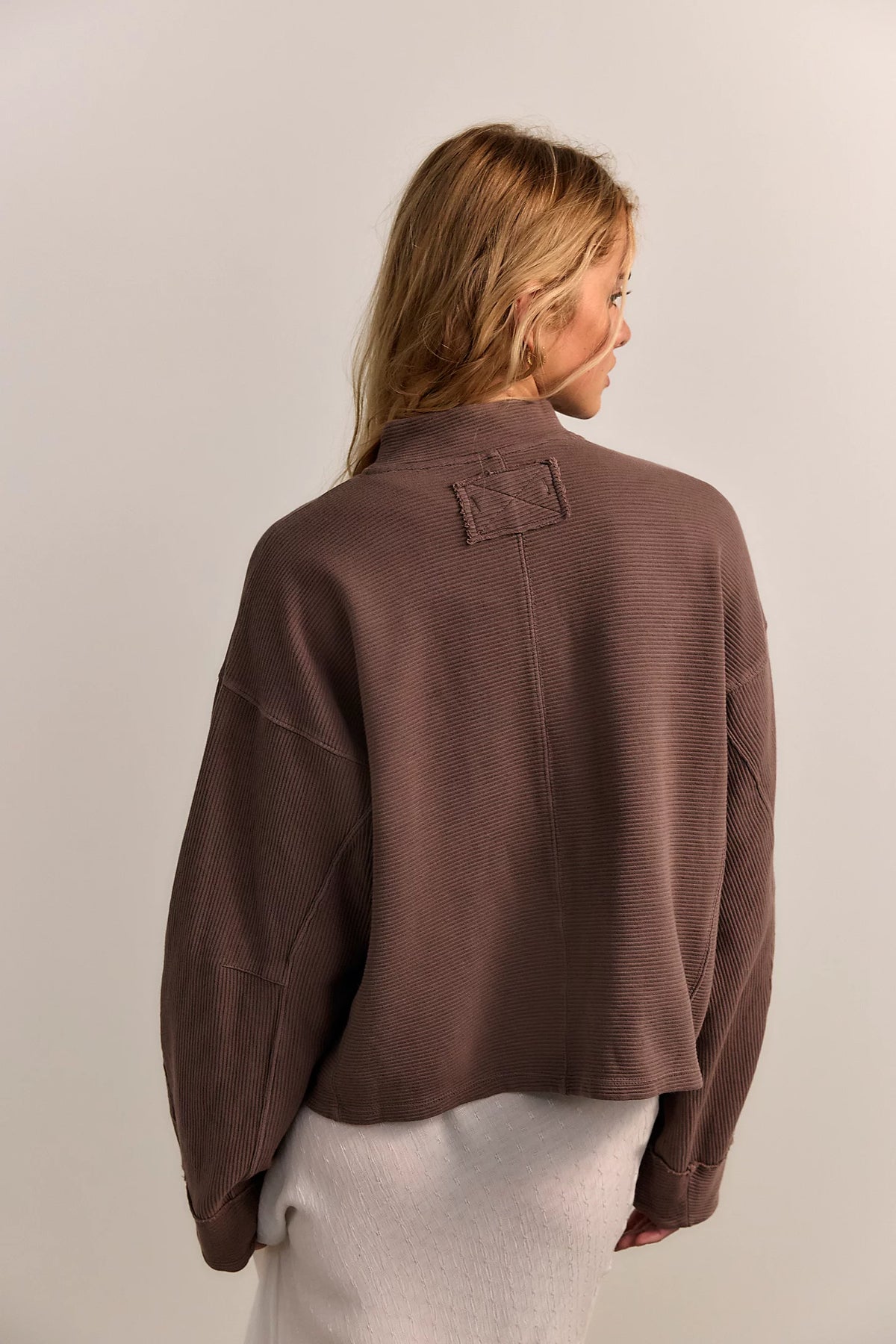 Person wearing a brown jacket on a plain background