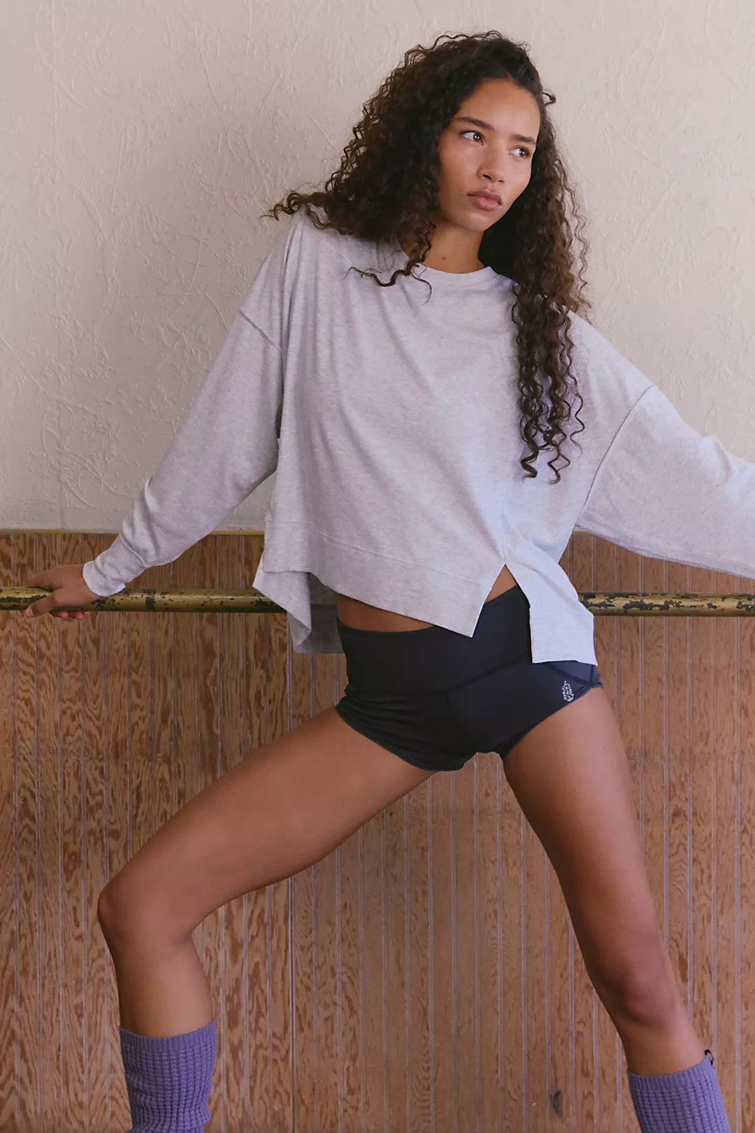 Woman wearing a long sleeve top that is heather grey with shorts