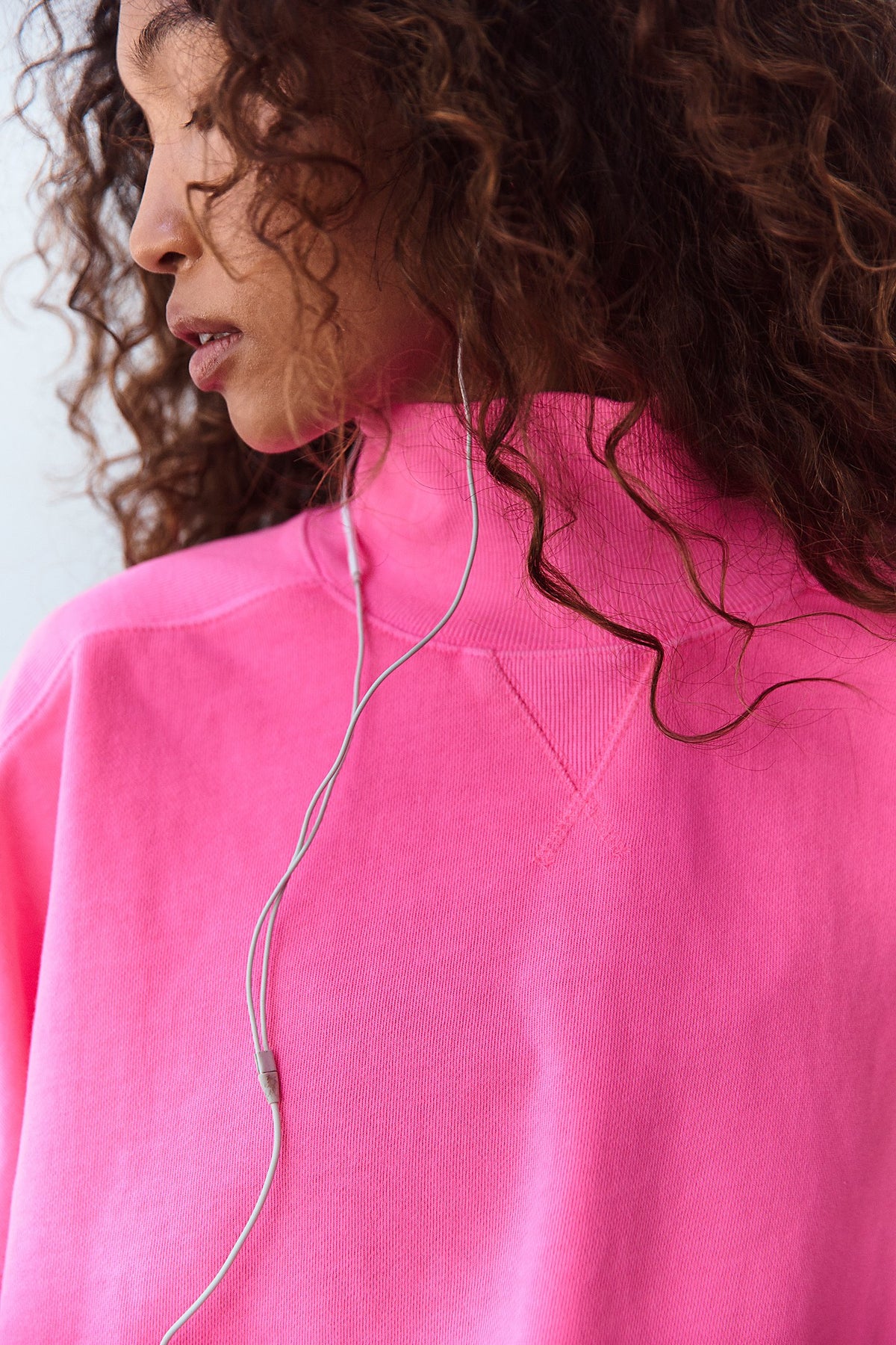 Women standing with pink sweatshirt and grey pants.