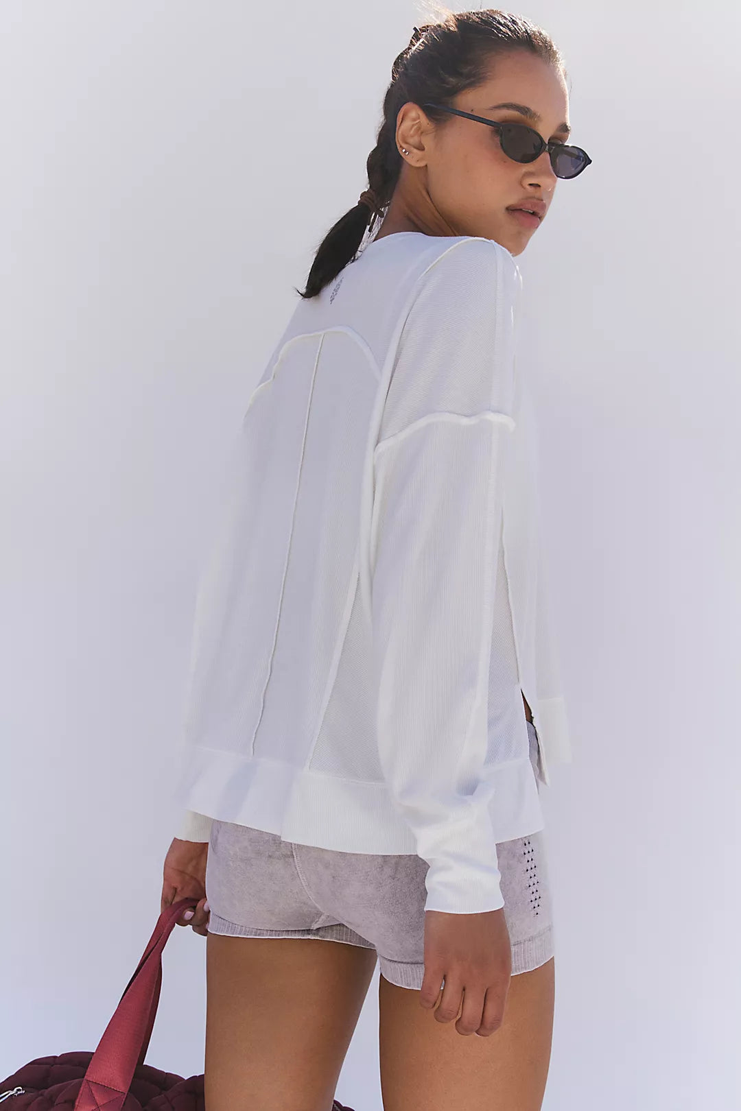 Woman wearing a long sleeve top that is white with shorts