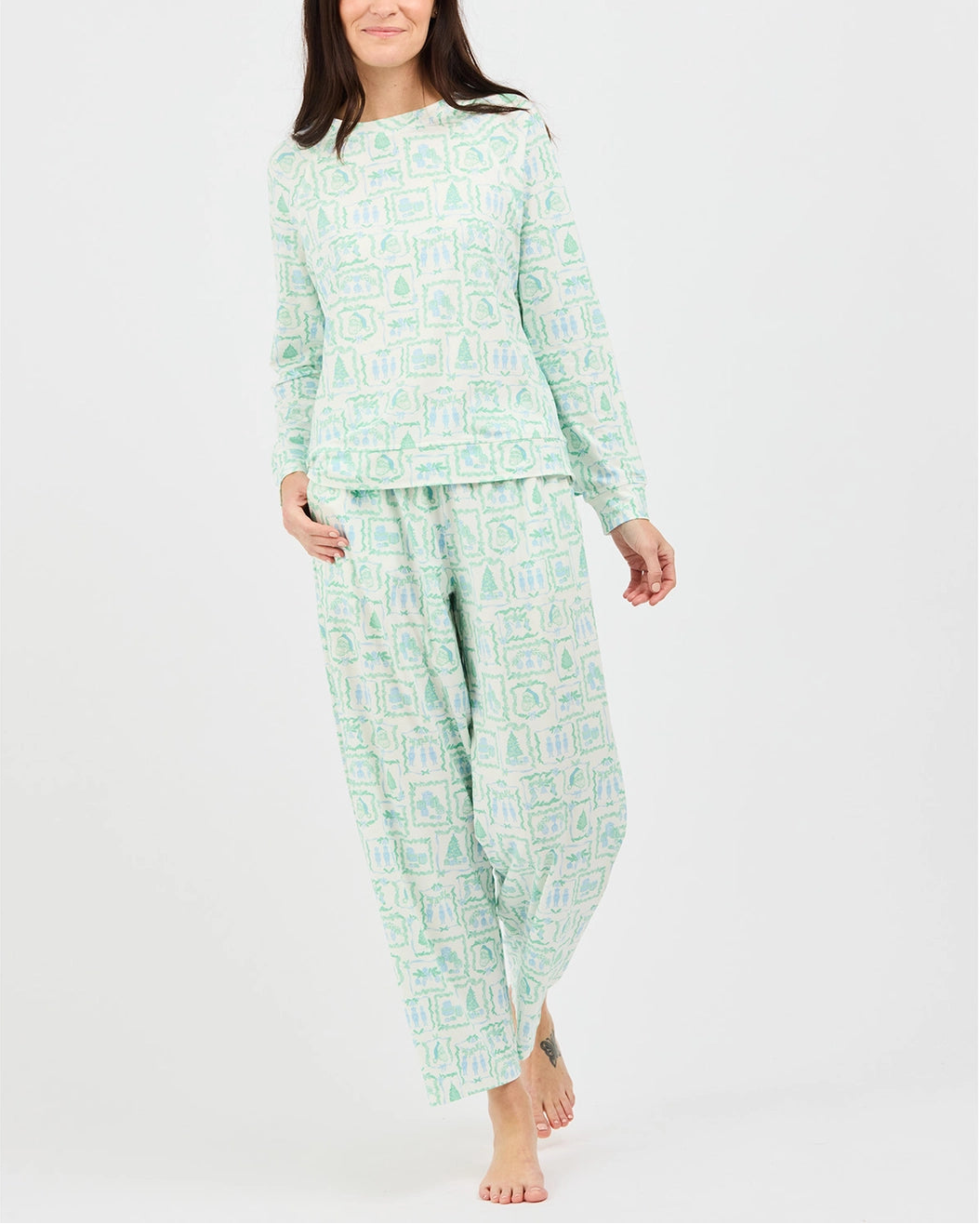 A woman modeling a two-piece long-sleeve pajama set with a light green and white geometric pattern, photographed against a plain light gray studio background.