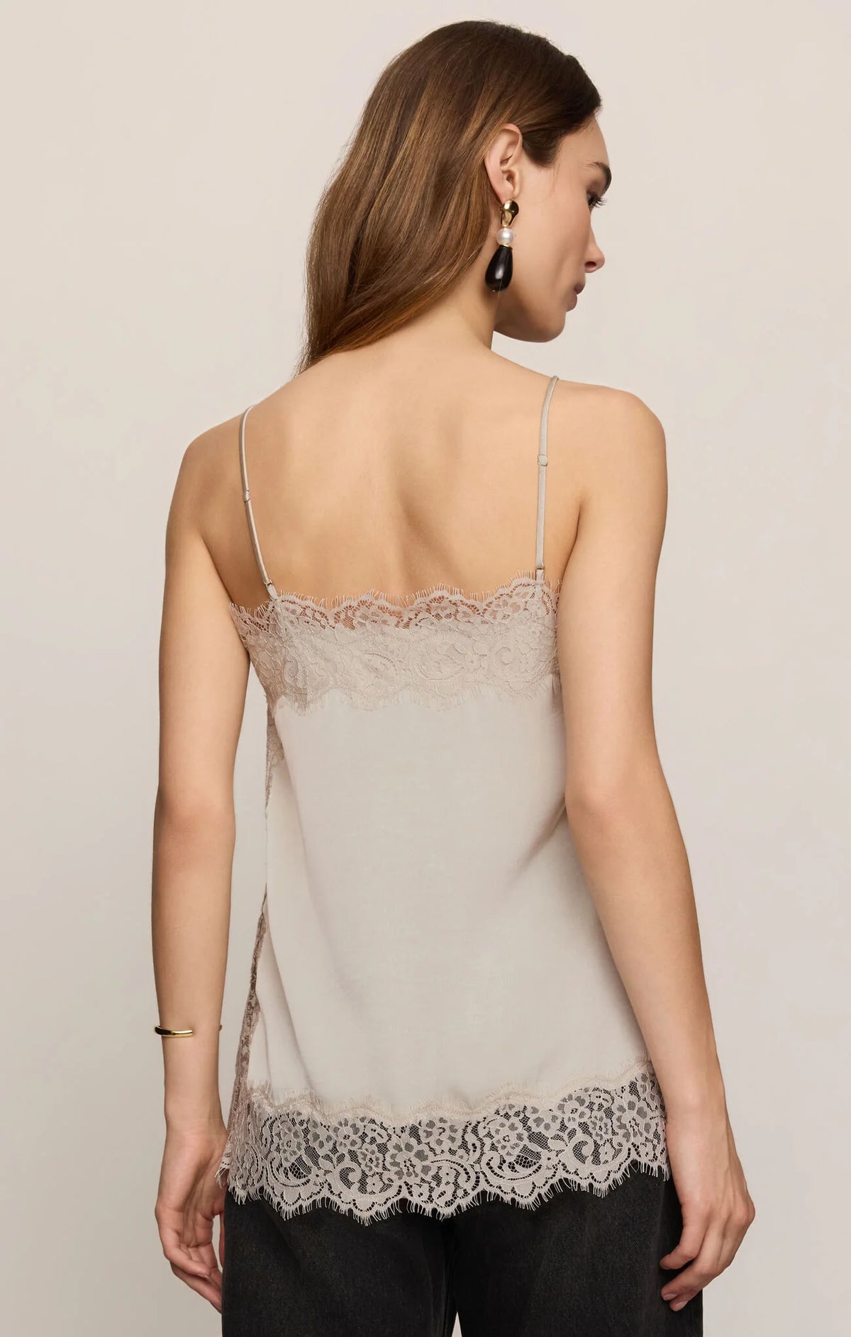 Woman modeling a silver lace trimmed tank against a cream background