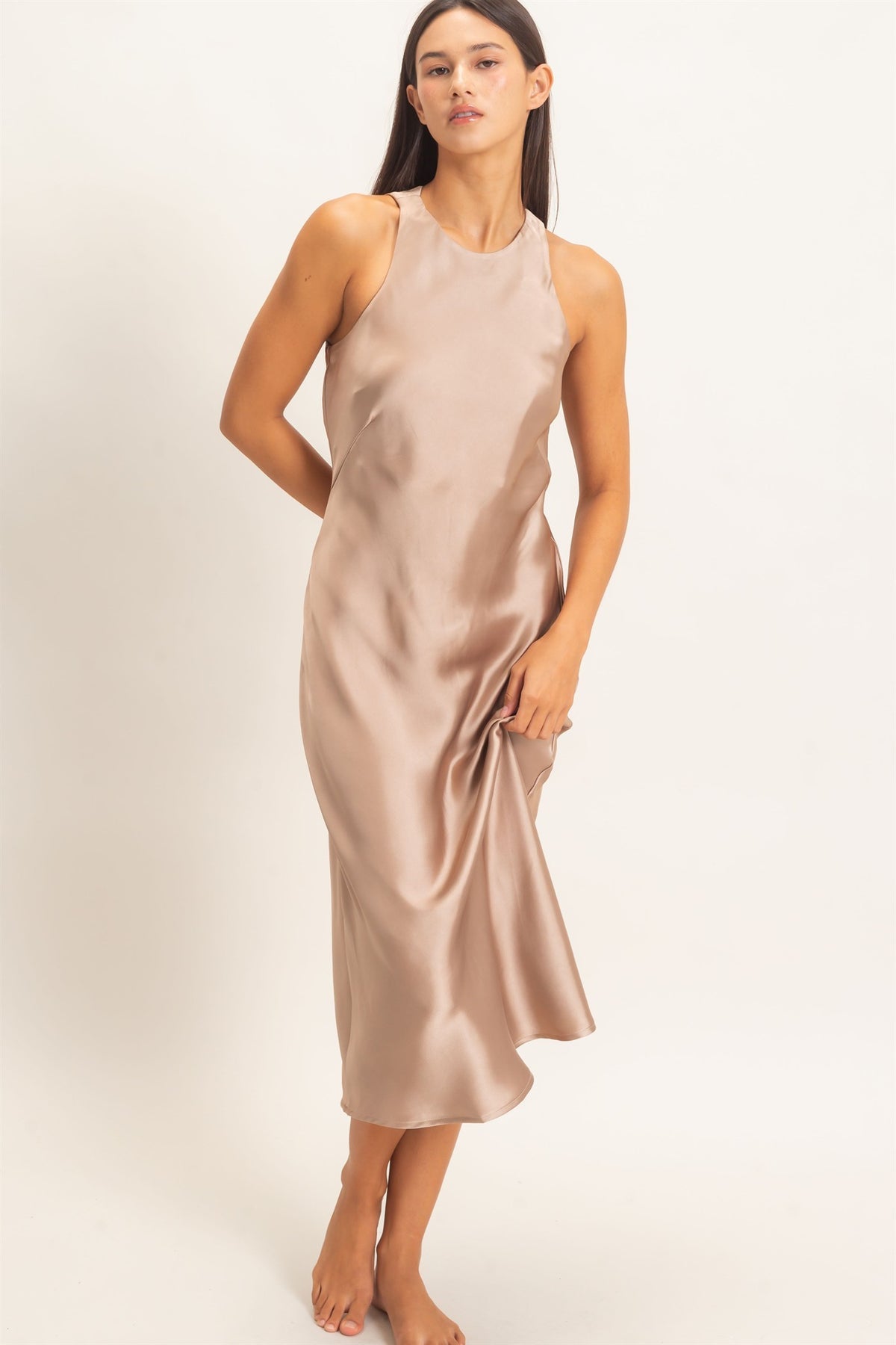 woman standing on white background wearing dark taupe satin dress 