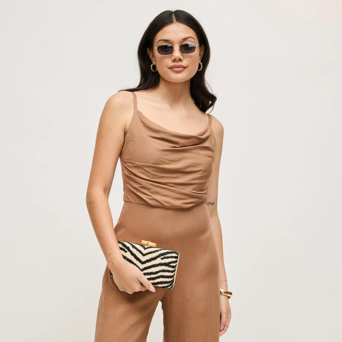 woman wearing sunglasses holding a zebra rectangle clutch 