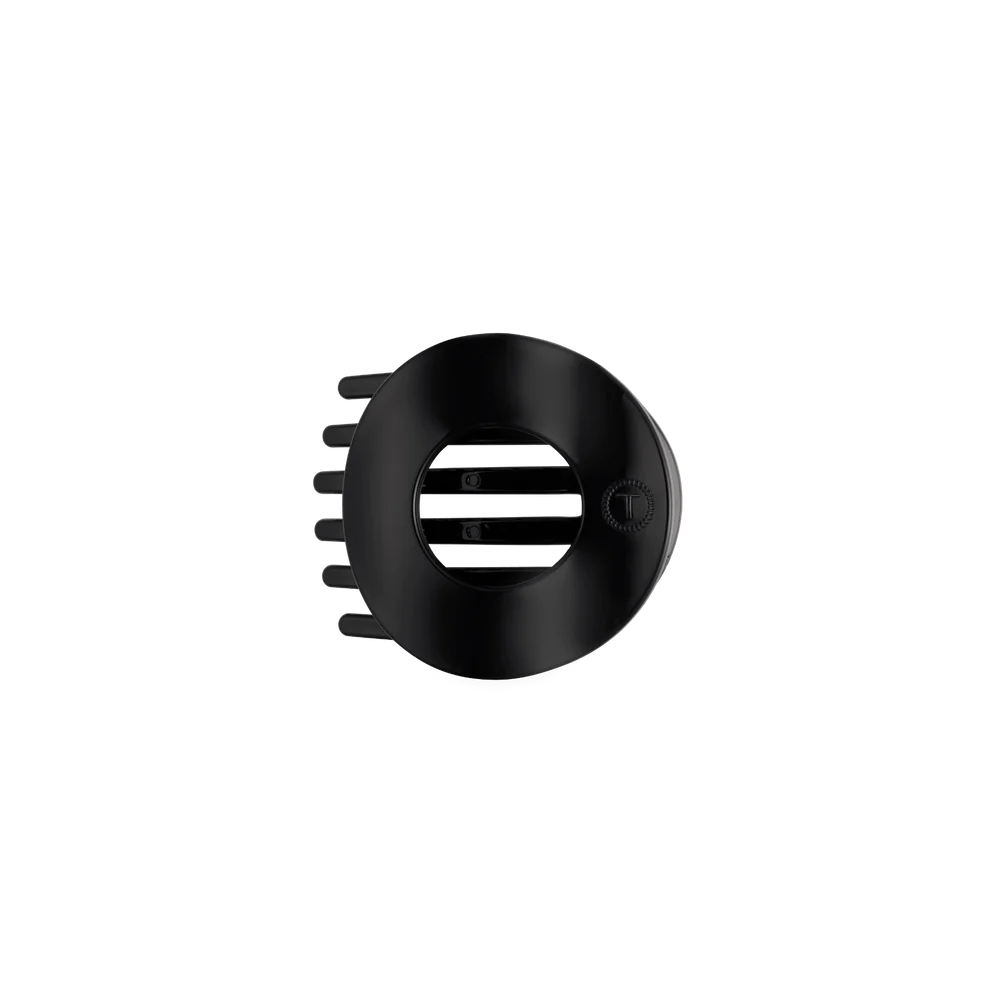 A matte black circular hair accessory with a central cutout and side teeth, shown on a plain white background.