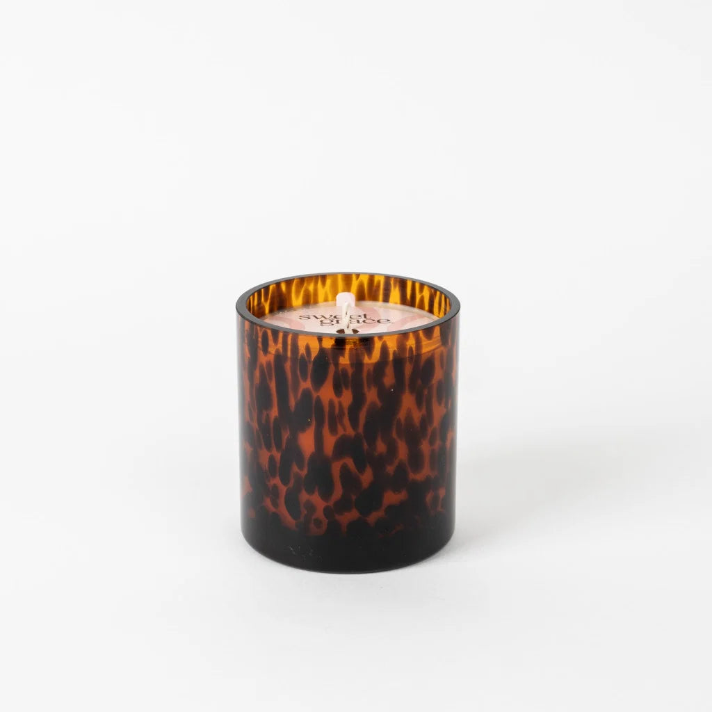Candle in a tortoiseshell-patterned container on a white background