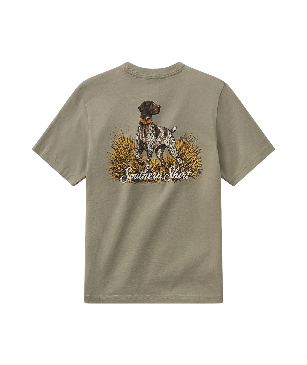A short-sleeve t-shirt in a muted khaki-beige color, featuring a graphic print of a hunting dog standing in a field with the text 'Southern Shirt' underneath.