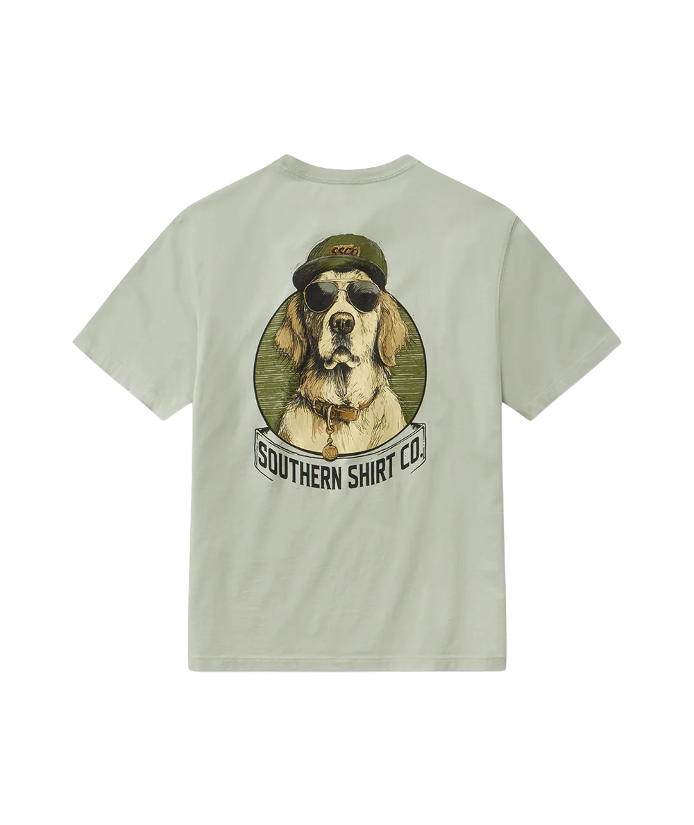 A sage green short-sleeve t-shirt shown from the back, featuring a large graphic print of a dog wearing sunglasses and a military-style cap inside an olive green circle, with a banner below reading 'SOUTHERN SHIRT CO!'.