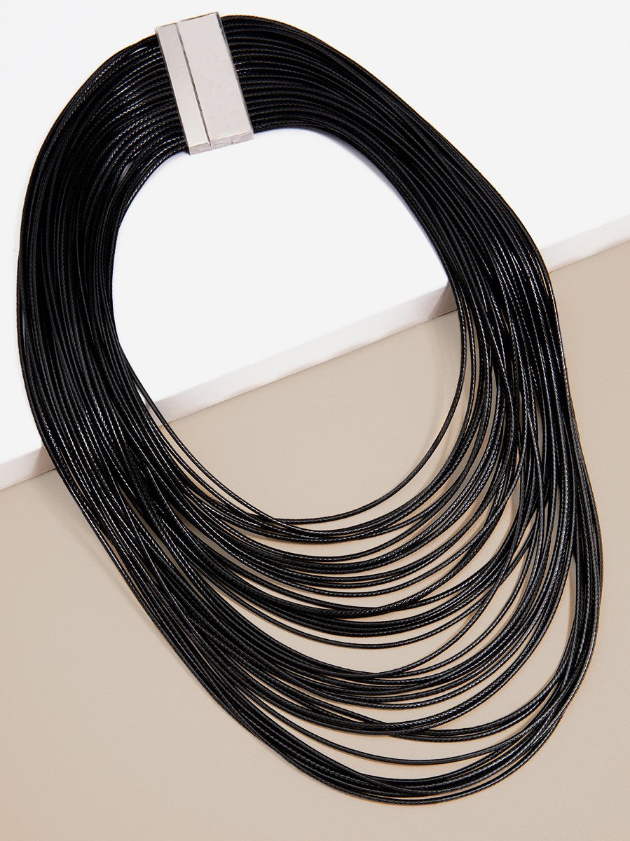 Black rope necklace with a silver clasp on a beige surface