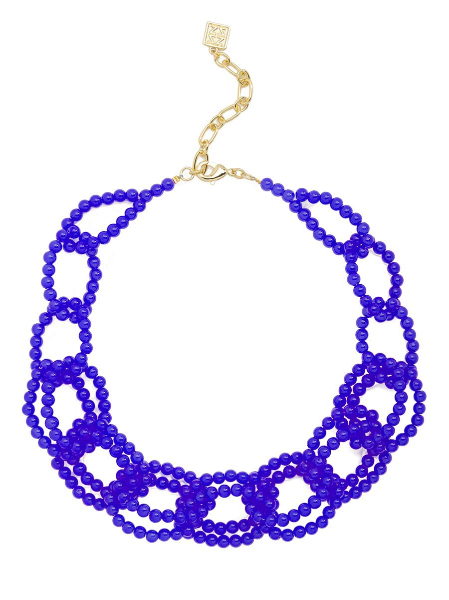A multi-strand beaded necklace in a vivid royal blue, featuring a gold-tone clasp and extender chain with a small square decorative charm, set against a plain white background.