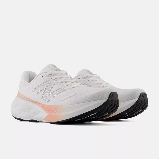 A pair of New Balance running shoes in white with a subtle peach gradient on the midsole and black outsole, shown against a light gray background.