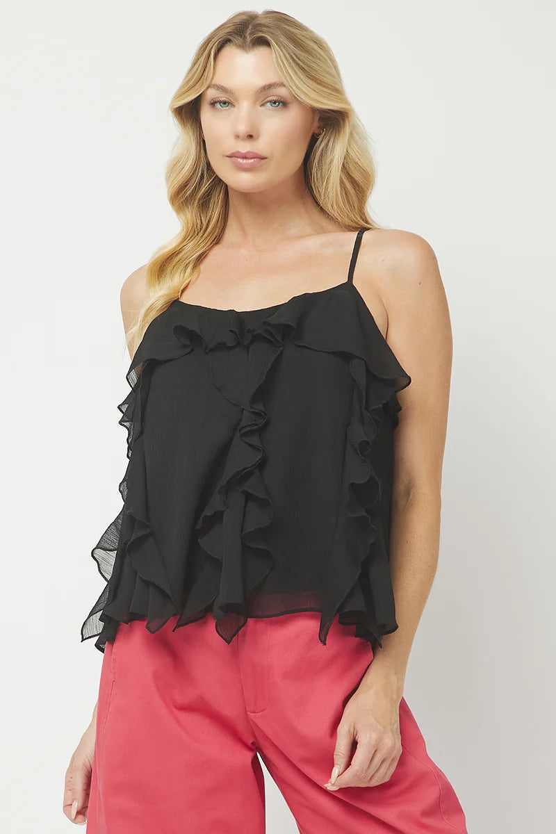 A blonde model wearing a black ruffled spaghetti-strap camisole top and bright pink pants, photographed against a light gray studio background.
