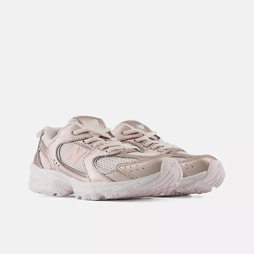 A New Balance low-top sneaker in metallic rose gold and silver mesh, featuring a chunky white midsole and a small white New Balance 'N' logo on the side.