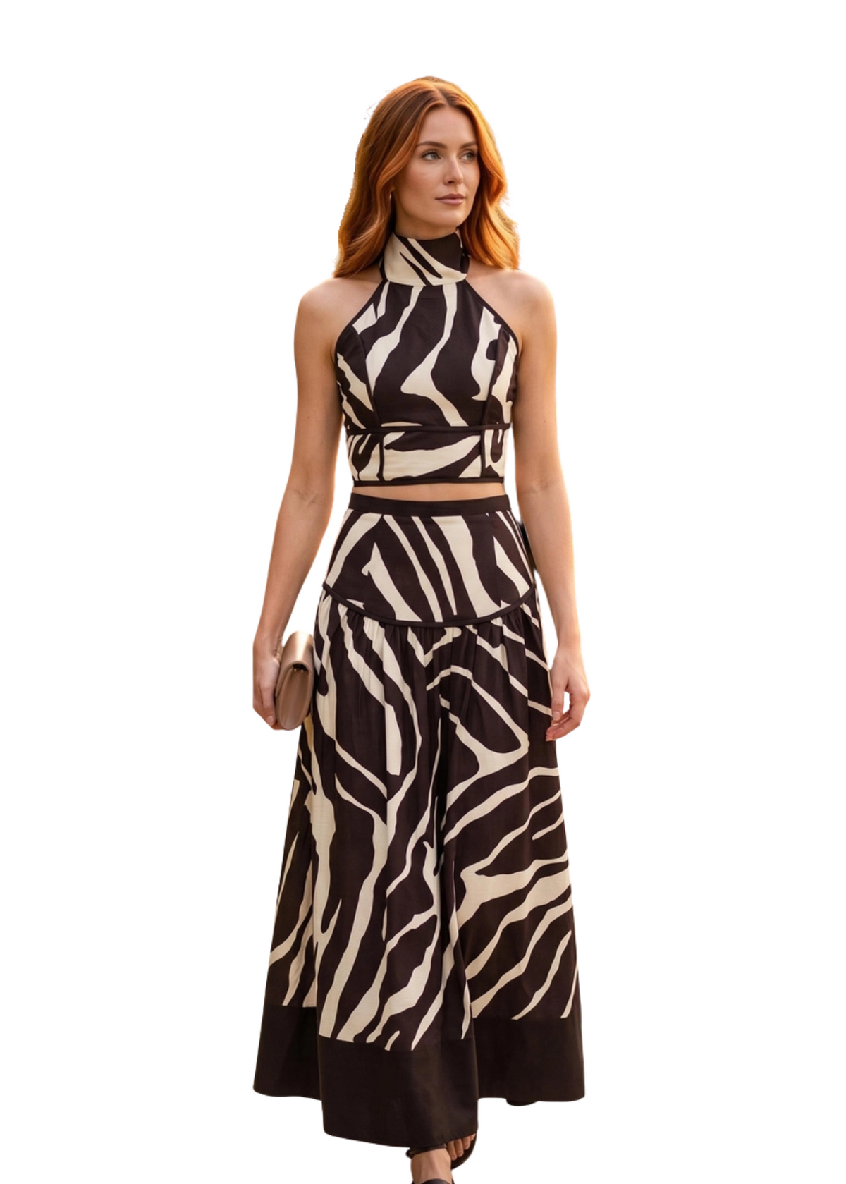 Woman wearing a brown and white zebra print halter top with a matching maxi high waisted skirt in front of a white background. 