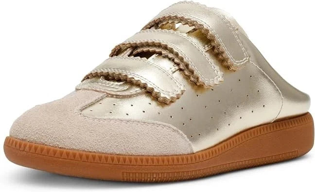 A single slip-on sneaker with a metallic gold upper, featuring two wide hook-and-loop straps with ruffled trim, a suede toe cap, and a brown gum sole, shown on a white background.