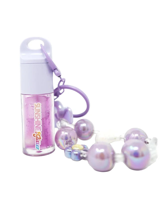 A small clear bottle of pink glitter lip gloss with a white cap and a purple carabiner clip, shown next to a matching iridescent pearl beaded bracelet on a white background.