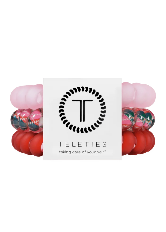A set of four Teleties hair stretch bands wrapped around a white branded card. The bands include solid light pink, solid red, and two marbled pink, green, and black patterns.