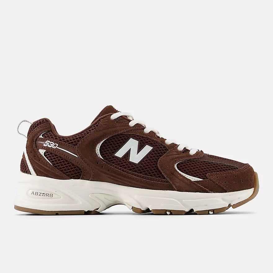 A New Balance 530 sneaker in brown suede and mesh with white laces, a white midsole, and a brown outsole, shown from a side profile on a white background.